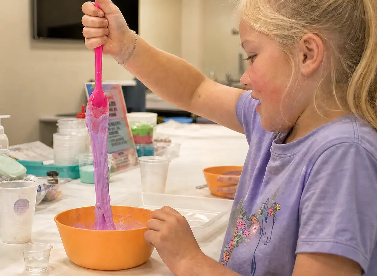 A child creating colorful slime at Cue the Party